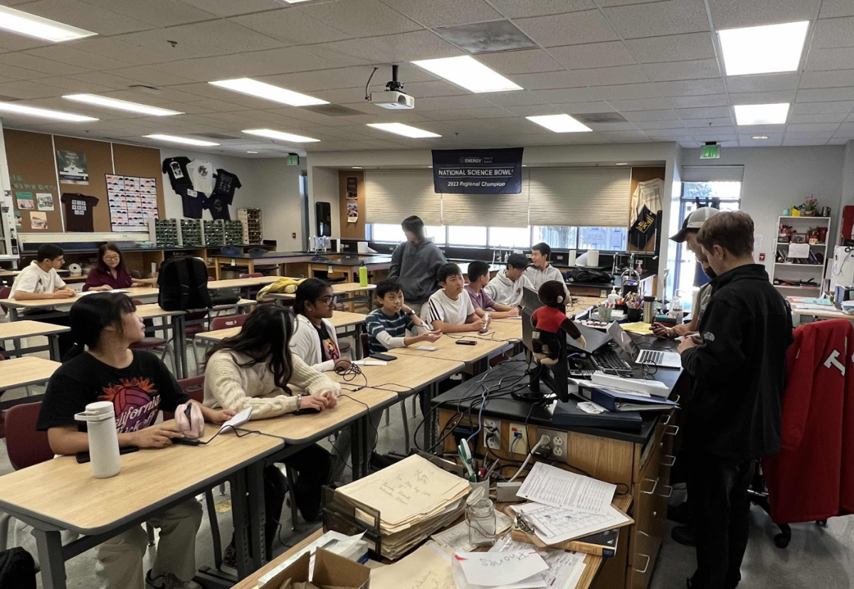 Junior vice captain Max Rombakh reads a packet to the Science Bowl team, as they practice buzzing.